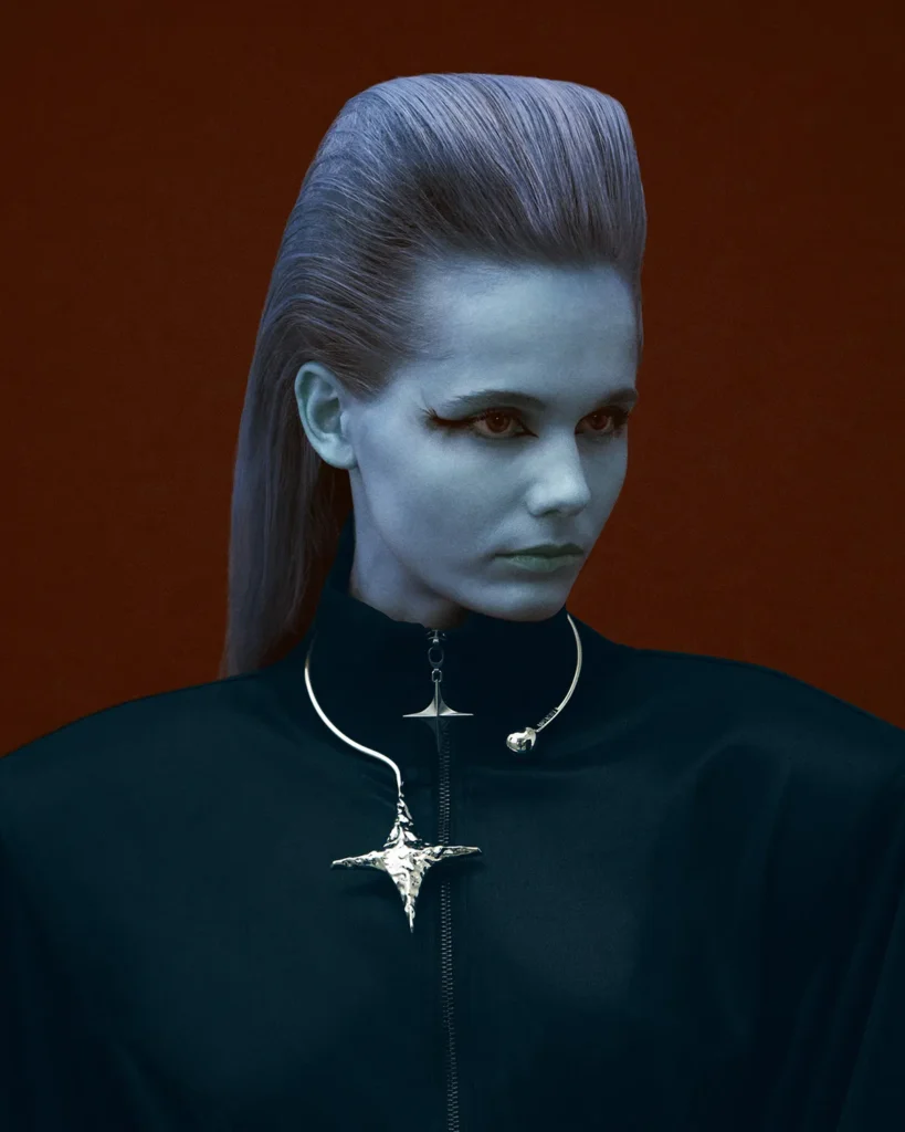 Portrait of a woman with blue-tinted skin, sculpted hair, and a metallic star-shaped necklace