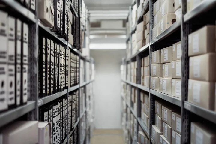 Rows of archive shelves filled with boxes and files, symbolizing order and aesthetic stillness.