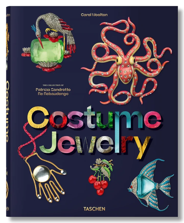 Cover of the TASCHEN book Costume Jewelry, featuring colorful vintage brooches including a jeweled octopus, a parrot with a green stone, cherries, a fish, and a hand-shaped pendant.