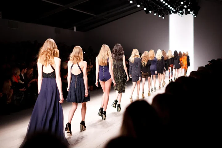 Models leaving the runway in formation at the end of a fashion show, seen from behind